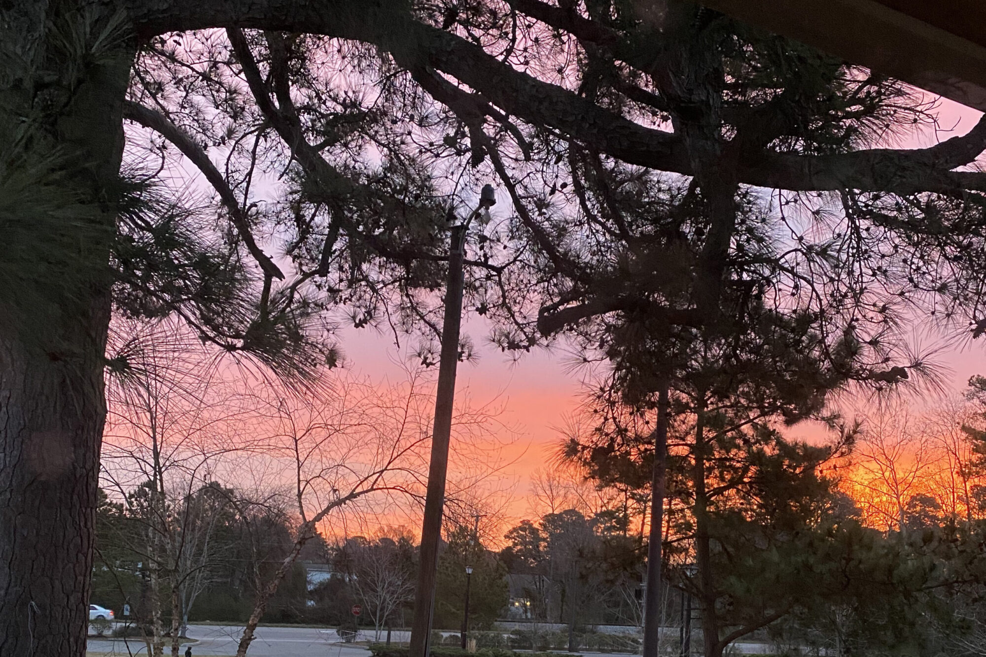 photo of the sun rising, tinting the sky with orange, pink, and purplish tones.